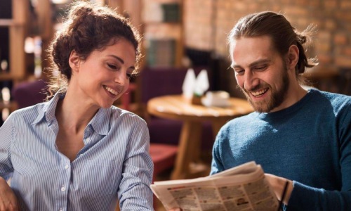a man and a woman sitting at a table looking at a book