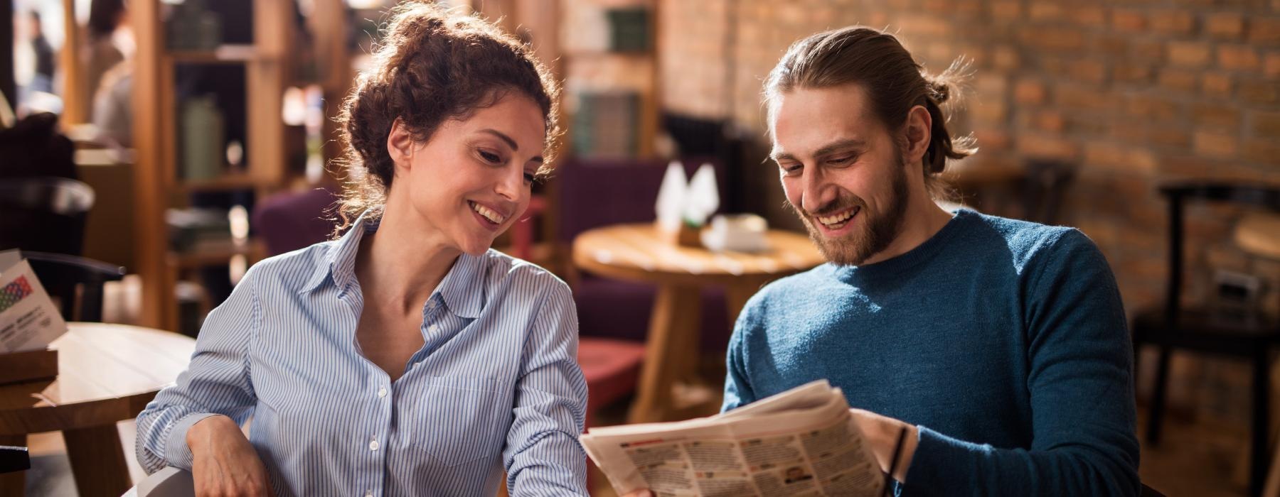 a man and a woman sitting at a table looking at a book